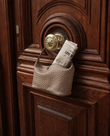 Gevlochten tas met krant aan een houten voordeur